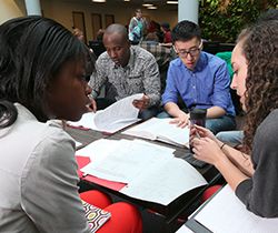 A group of racially diverse students students discussing course work