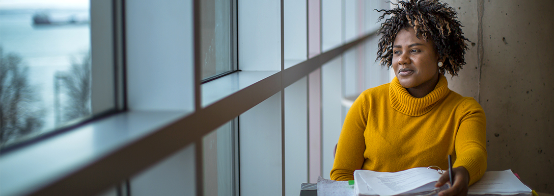 Une étudiante noire regarde par la fenêtre du Nova Scotia Community College