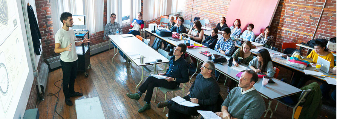 Un étudiant blanc présente son travail devant sa classe et ses professeurs à NSCAD University 